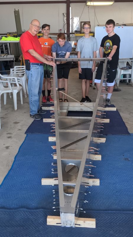 teens and a mentor pose with the work in progress